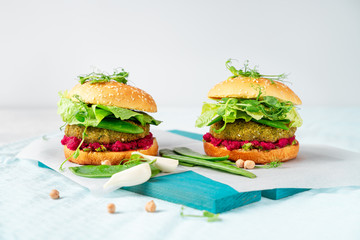 Homemade vegan burgers with chickpea pattie, green peas and beetroot hummus on white background