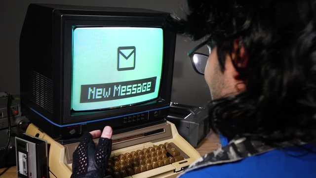 Vintage computer nerd excited about receiving a new message on a retro computer from 70s 80s. Old technology concept.