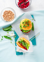 Homemade vegan burgers with chickpea pattie, green peas and beetroot salsa on pale blue background, top view