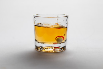 Studio shot of rum on white background in shot glass whit a pill