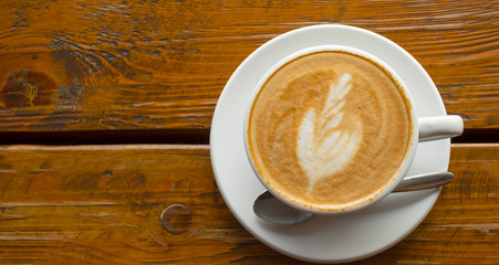 latte coffee with latte art palm leaf-shaped in a classic white coffee cup