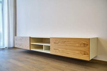 Floating media cabinet in contemporary living room. Wooden wall mounted cabinet