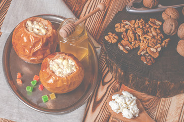 healthy food. Baked apples with cottage cheese and nuts lie in a black baking dish on a wooden table