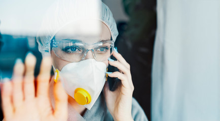 Quarantine during the virus outbreak at home or in a hospital, woman looking through the window