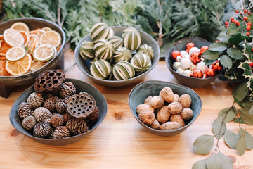 Base for Christmas wreath. Christmas decorations. Florist making Christmas wreath. View of female hands make a wreath. Decorations for wreath. Oranges, flowers red berries, wooden stars.