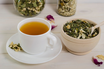 A cup of herbal tea and dried herbs on a white wooden table. To enhance immunity, a natural remedy for health.