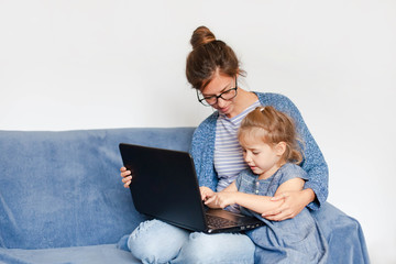 Working from home with kids. Mother and daughter using laptop and Internet. Freelancer workplace....