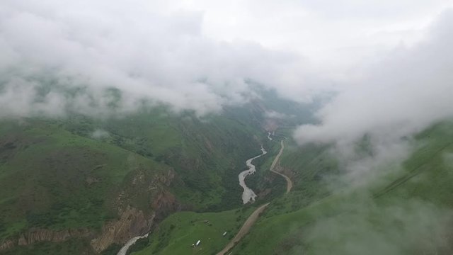 Aerial footage clouds in mountains, road and mountain river