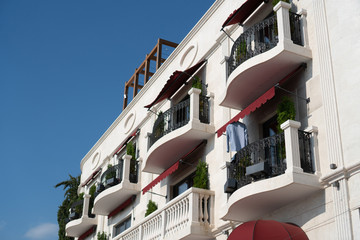 Facade of a white building with wrought-iron balconies and red awnings