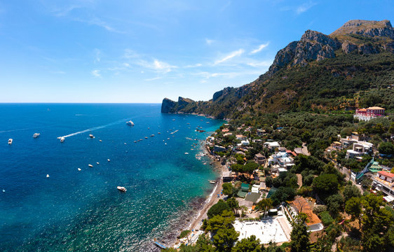 Aerial view of coastline of the village of Nerano. Private and wild beaches of Italy. Turquoise, blue surface of the water. Vacation and travel concept. Boats on raid in bay. Copy space. Summer day