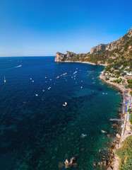 Fototapeta na wymiar Aerial view of coastline of the village of Nerano. Private and wild beaches of Italy. Turquoise, blue surface of the water. Vacation and travel concept. Boats in bay. Copy space. Vertical photo