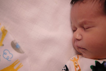 Newborn infant baby boy sleeping in a crib