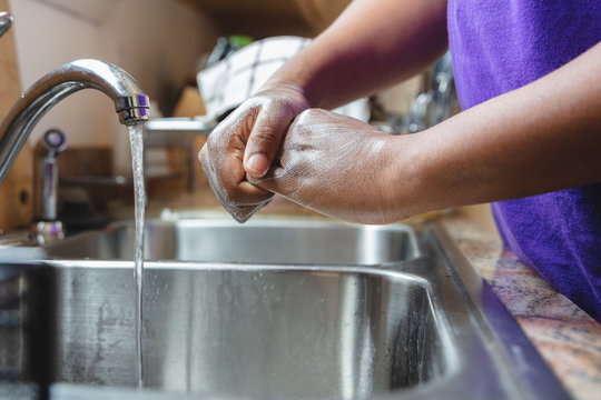 Black man washing hands in sink