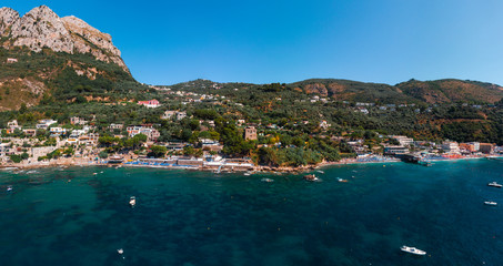 Fototapeta premium Aerial view of coastline of the village of Nerano. Private and wild beaches of Italy. Turquoise, blue surface of the water. Vacation and travel concept. Boats on raid in bay. Copy space. Summer day