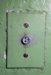 Close-up of old elevator button. Ancient soviet button on concrete wall with dirty and peeling paint.