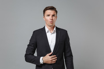 Shocked amazed young business man in classic black suit shirt posing isolated on grey wall background studio portrait. Achievement career wealth business concept. Mock up copy space. Looking camera.
