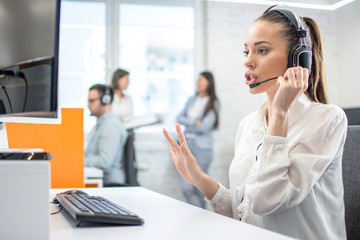 Beautiful female customer support phone operator at workplace.