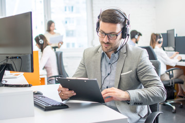 Male customer support agent with clipboard working in office