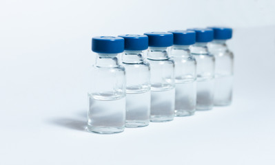 Glass medicine bottles with injection fluid with blue aluminium caps for vaccination. Coronavirus epidemic, Cancer, painand diabetes treatment, pharmaceutical medicine concept .