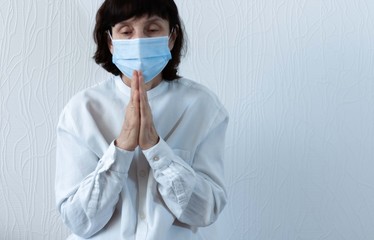 Coronavirus quarantine and Air pollution pm2.5 concept. Old sick woman wearing blue respirator mask for protect and praying to god. Wuhan, China epidemic virus symptoms background.