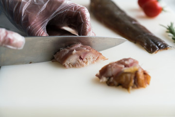 Closeup of a chef cutting resh fish fillet with a knife. Food background, ingredients on the table. Healthy food, styling, cooking concept.