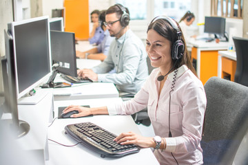 Young female technical support with hands-free device at call center - obrazy, fototapety, plakaty