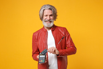 Blinking elderly gray-haired mustache bearded man isolated on yellow background. People lifestyle concept. Mock up copy space. Hold modern bank payment terminal process acquire credit card payments.