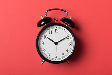 Black vintage alarm clock on red background. Time concept