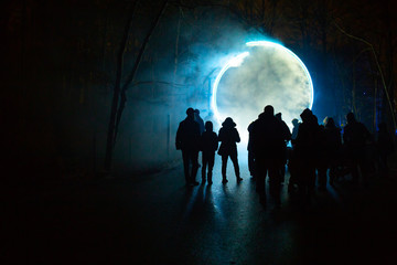 Fototapeta na wymiar Colored circle light with silhouette of people walking toward it