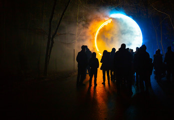 Colored circle light with silhouette of people walking toward it