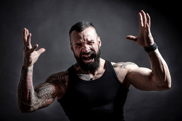 Uomo tatuato con barba urla arrabbiato , isolato su sfondo nero