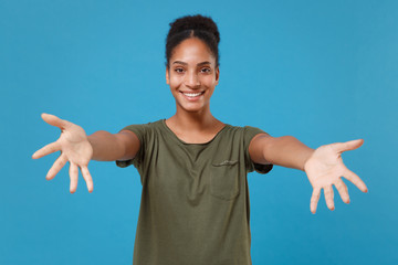 Funny young african american woman girl in casual t-shirt posing isolated on blue background studio portrait. People lifestyle concept. Mock up copy space. Standing with outstretched hands for hugs.