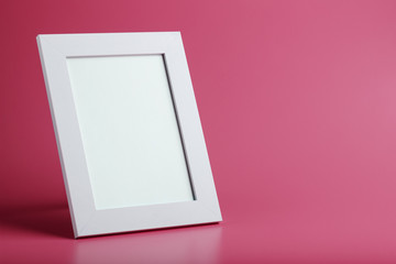 White photo frame with an empty space on a pink background.