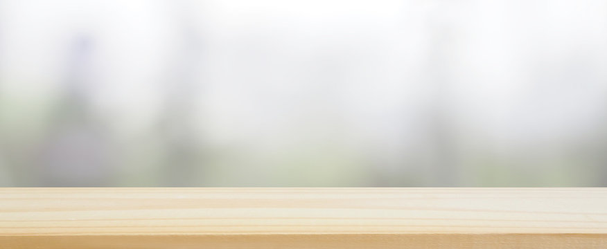 wood plank table top on blur abstract green tree , leaves and kitchen window and see view the gardening behind for banner design and natural background or montage display product layout