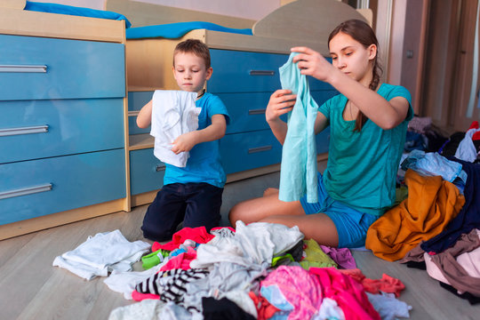 Happy children folding clothes in thier bedroom