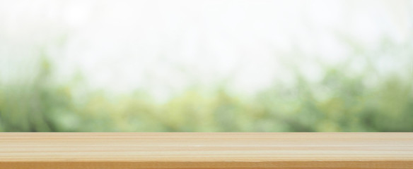 wood plank table top on blur abstract green tree and leaves in the garden in the morning using for...