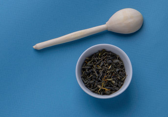 dry green tea with thyme and wooden spoon on the blue background