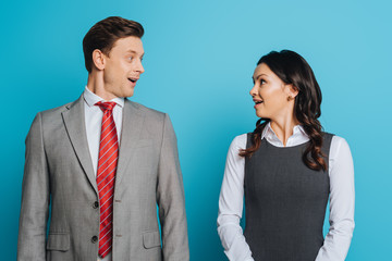 two surprised businesspeople looking at each other on blue background