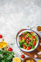Fresh vegetable salad with dressing of mustard, olive oil, garlic, lemon and herbs in a plate on a gray concrete background, top view, copy space. Healthy mediterranean cuisine, vegetarian food