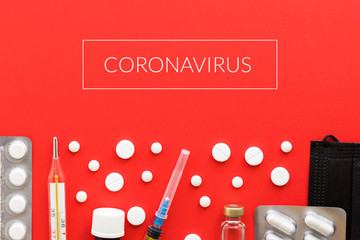 White pills, syringe, medical mask, vassine vial, plastic bottle on red background. COVID-19 coronavirus pandemic, painkillers, healthcare concept. Medical injection.
