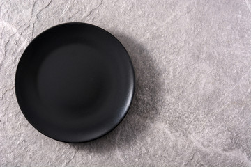 Empty black plate on gray background. Top view copy space