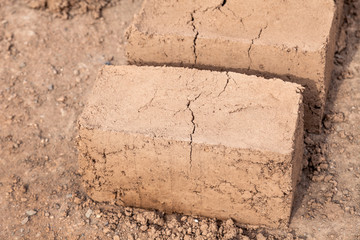 Traditional homemade production of raw clay brick laid out in stacks for drying on brick factory