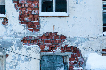 Old concrete wall with broken windows. Abandoned district. Russian far North