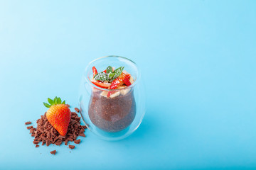 Chocolate Chia pudding decorated with strawberry on blue background