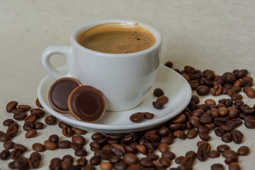 A cup of strong coffee. Coffee in a white cup on a saucer. Coffee beans.