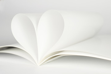 Two blank magazine pages that becomes one heart shape. Clean photo of magazine on white background, as concept for valentines day, love stories etc.