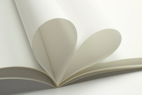 Two blank magazine pages that becomes one heart shape. Clean photo of magazine on white background, as concept for valentines day, love story etc.