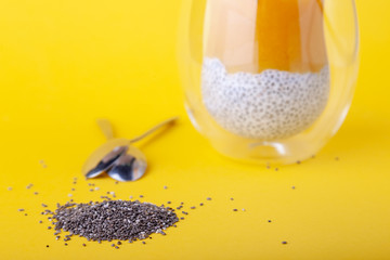 Mango pudding with chia seeds in glass on yellow background