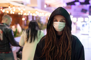 girl in a medical mask to a black hood in a shopping center