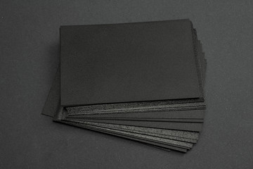 stack of black blank textured business cards on dark paper background, us size 3.5 x 2 inches, as template for design presentation.